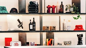 Ein modernes Interieur mit einer zentralen, schwarz-weiß gestreiften Theke, gläsernen Auslagenregalen mit verschiedenen Artikeln und einem minimalistischen Design.
