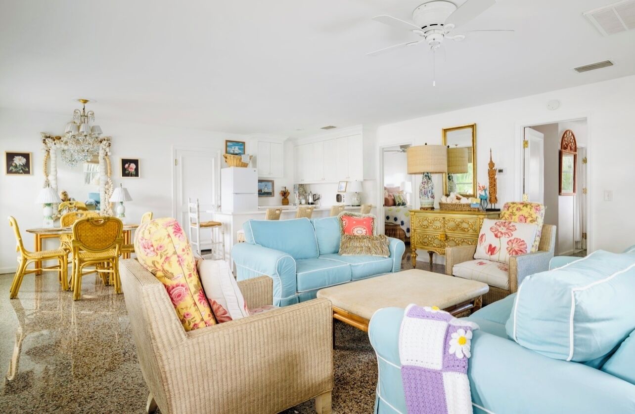 A spacious living room with a dining area, a kitchen, and a large chandelier.
