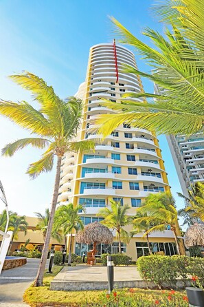 A tall, multi-story hotel with balconies and a clear sky.