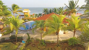 Ein Resort mit Schwimmbad, Palmen und Blick auf den Ozean.