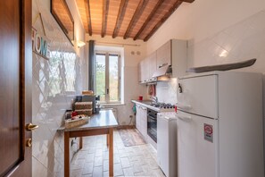 Una cucina con soffitto in legno, una finestra, un lavello e un frigorifero.