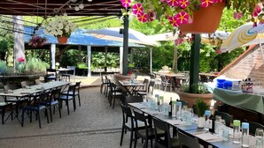 An outdoor dining area with tables and chairs, hanging flower baskets, and umbrellas.