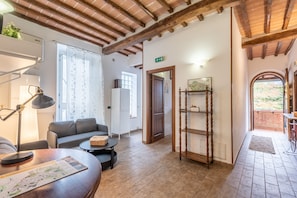 A cozy room with a sofa, a small table, a lamp, a wooden shelf, and a door leading to another room. - Podere La Miniera Relax & Food with Shared Garden and Wi-Fi (Siena)