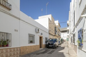 A narrow street with parked cars, white buildings, and a clear blue sky. - Holiday Home 'Mudarra Conil' with Private Terrace, Wi-Fi and Air Conditioning (Conil de la Frontera)