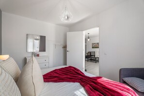 Une chambre à coucher comprenant un lit, une commode, un miroir et une porte donnant sur une autre pièce.