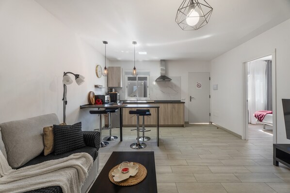 Un salon moderne avec un canapé, une table basse et une cuisine en arrière-plan.