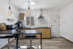 A modern kitchen with a central island, pendant lighting, and a microwave. - Holiday Apartment '3 Apartamentos Omanai Tenerife Sur' with Shared Garden & Wi-Fi (Las Galletas)