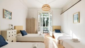 Une chambre d’hôtel avec deux lits, une armoire en bois, un bureau et une grande fenêtre.