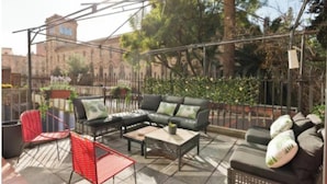 Un espace extérieur aménagé en terrasse, avec un ensemble de canapés, des chaises rouges et une table basse.