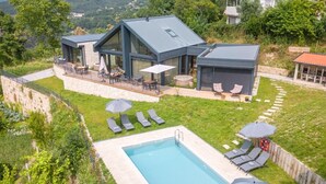 Et moderne hus med swimmingpool, udendørs siddepladser og udsigt over de omkringliggende bakker.