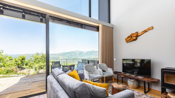 A modern living room with a large sofa, two armchairs, a TV, and a wooden coffee table.
