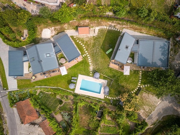 An aerial view of a residential area with multiple houses, a swimming pool, and a well-maintained garden.