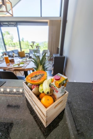 Une caisse en bois remplie de fruits et un carton de jus sur un plan de travail de cuisine.