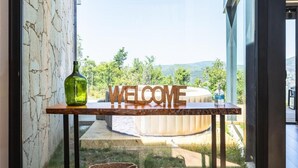 A modern interior with a 'WELCOME' sign, a glass door leading outside, and two woven baskets on the floor.