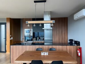 A modern kitchen with a central island, built-in appliances, and a dining area with chairs.