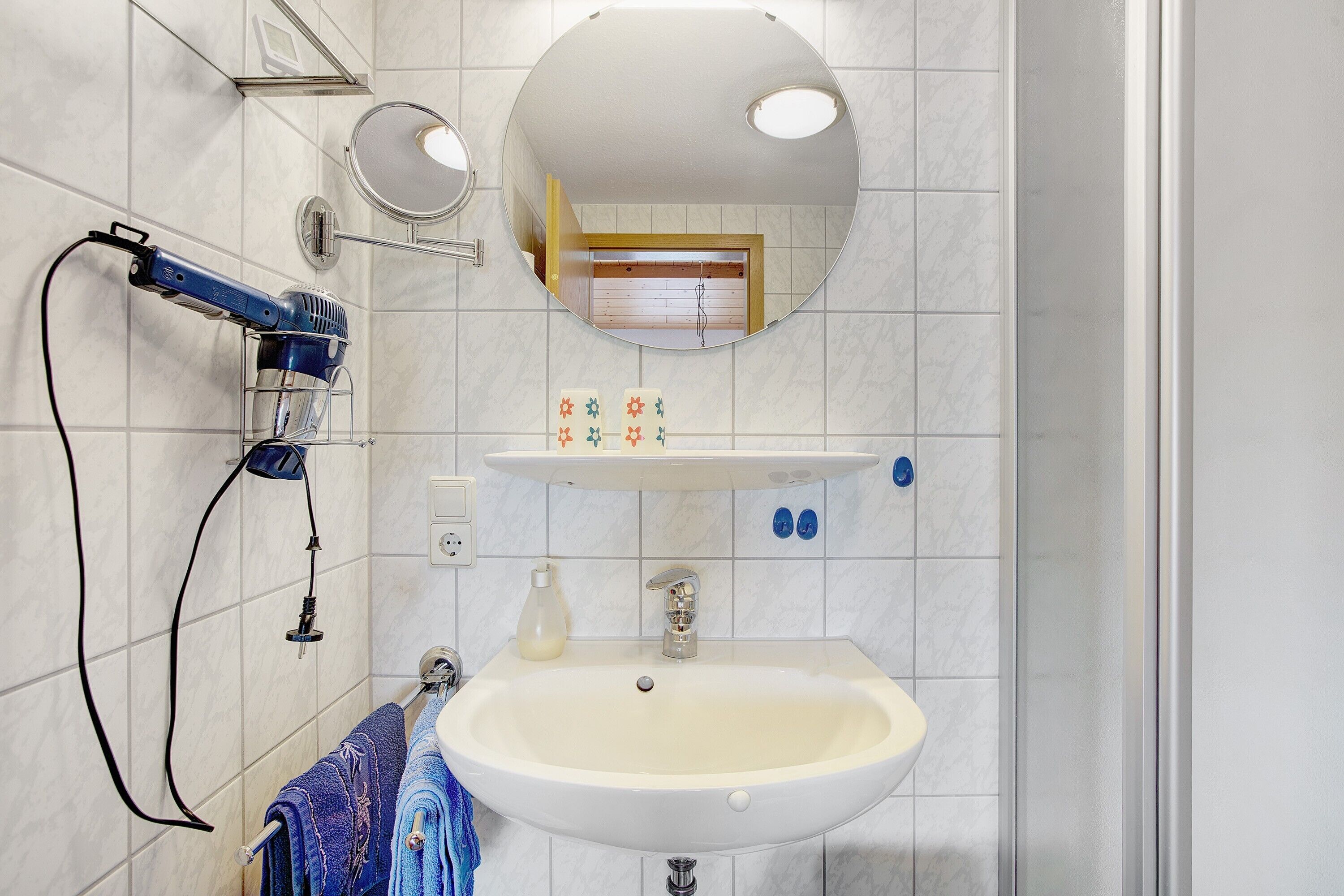 A bathroom with a sink, mirror, towel rack, and a hairdryer.