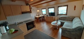 Cocina compacta con comedor, sofá y televisor.