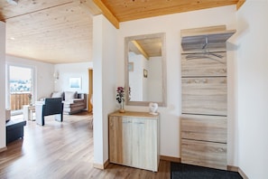Ein modernes Interieur mit Holzboden, einer Couch, einem kleinen Tisch, einem Schrank und einem Spiegel.