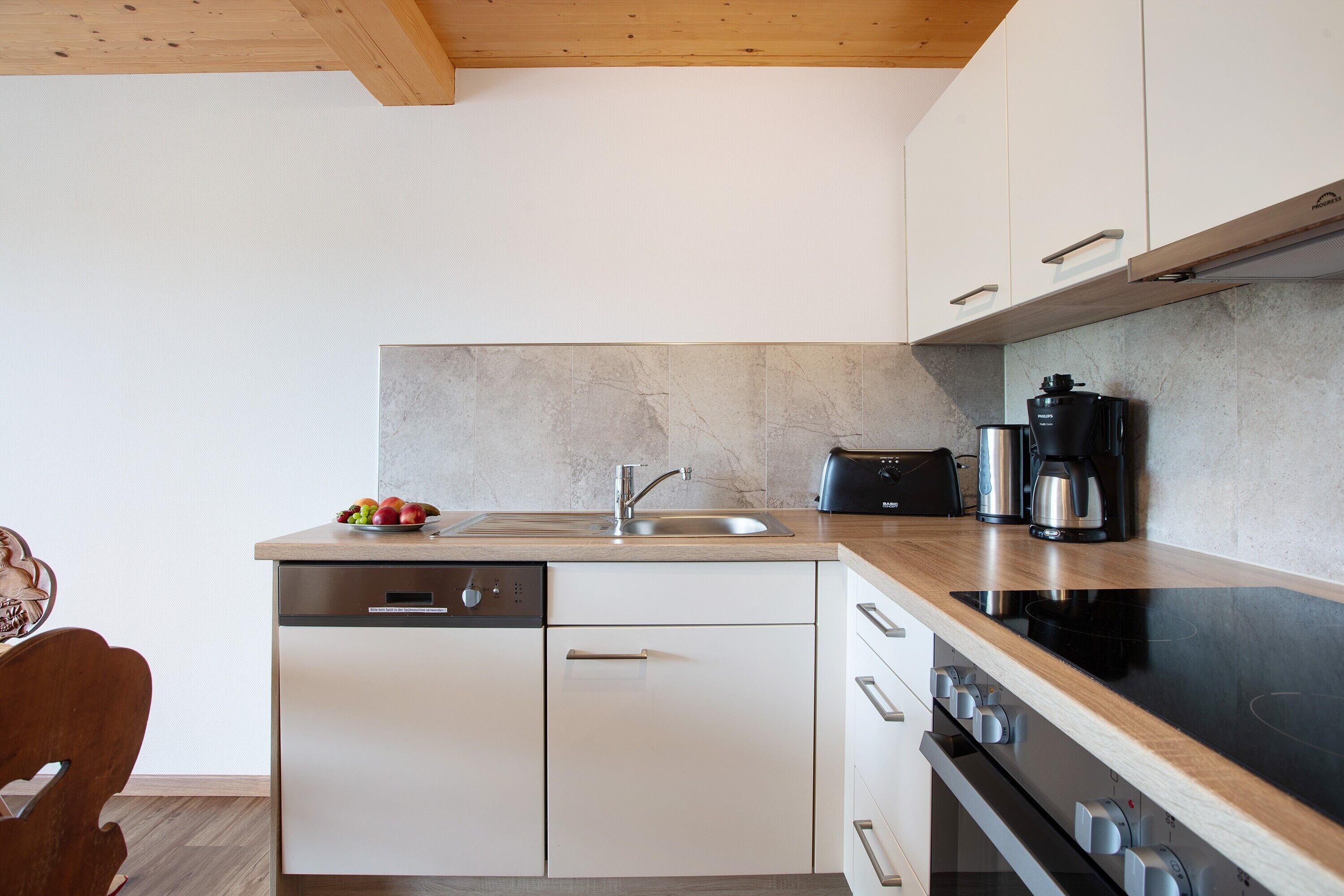A modern kitchen with a dishwasher, stove, and coffee maker.