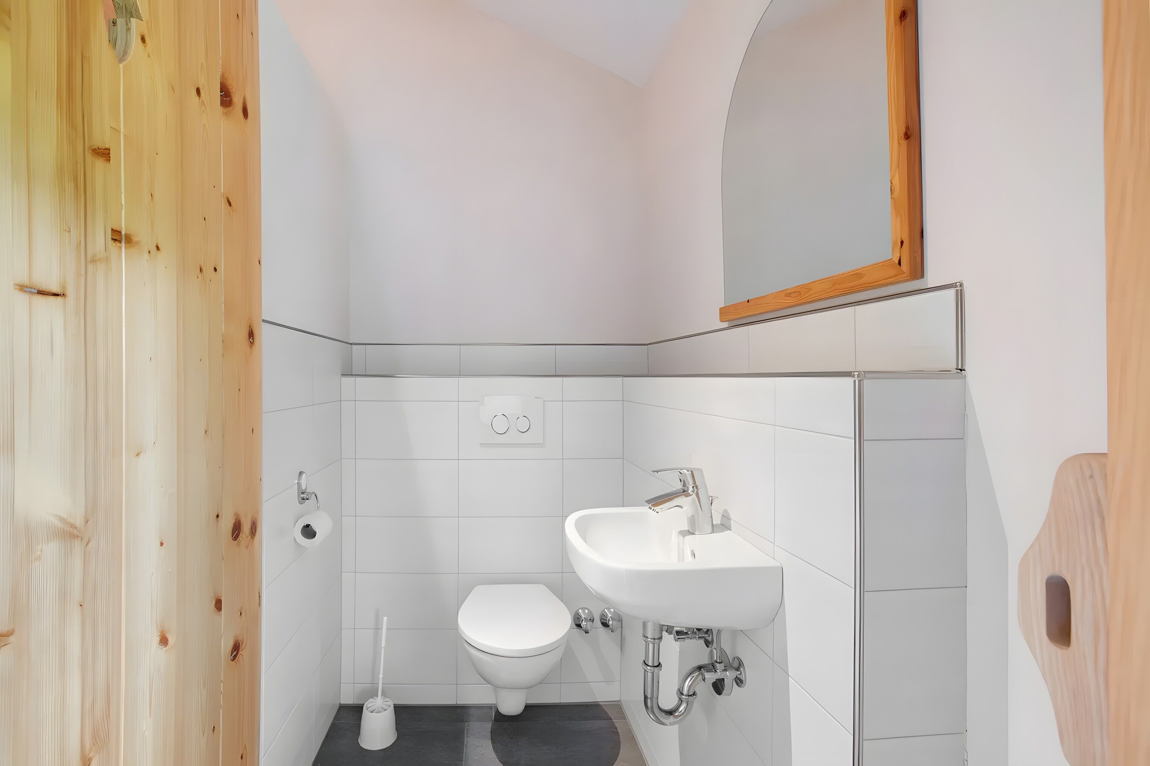 Ein kleines Badezimmer mit Toilette, Waschbecken und Spiegel.