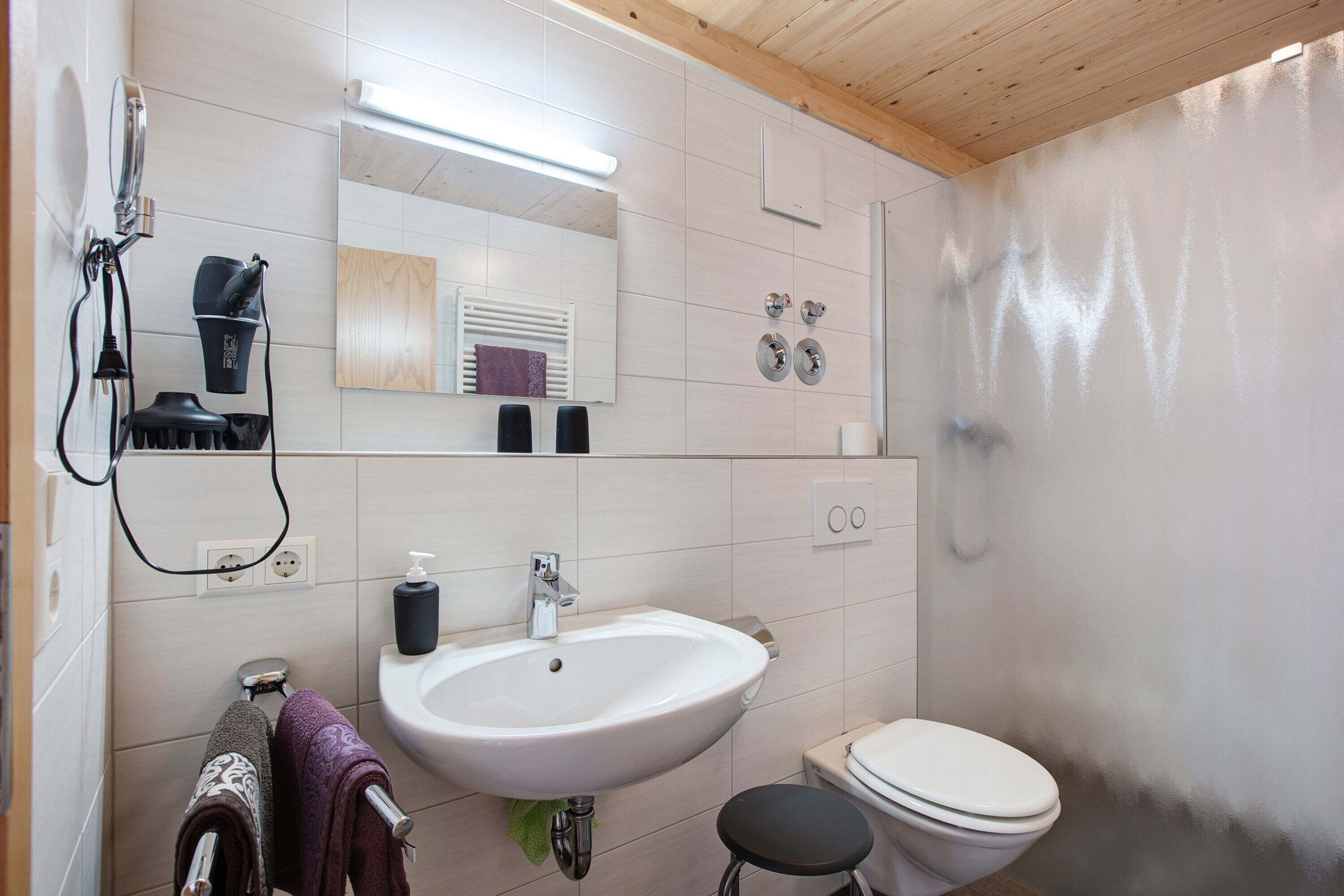 A bathroom with a white sink, mirror, and toilet.