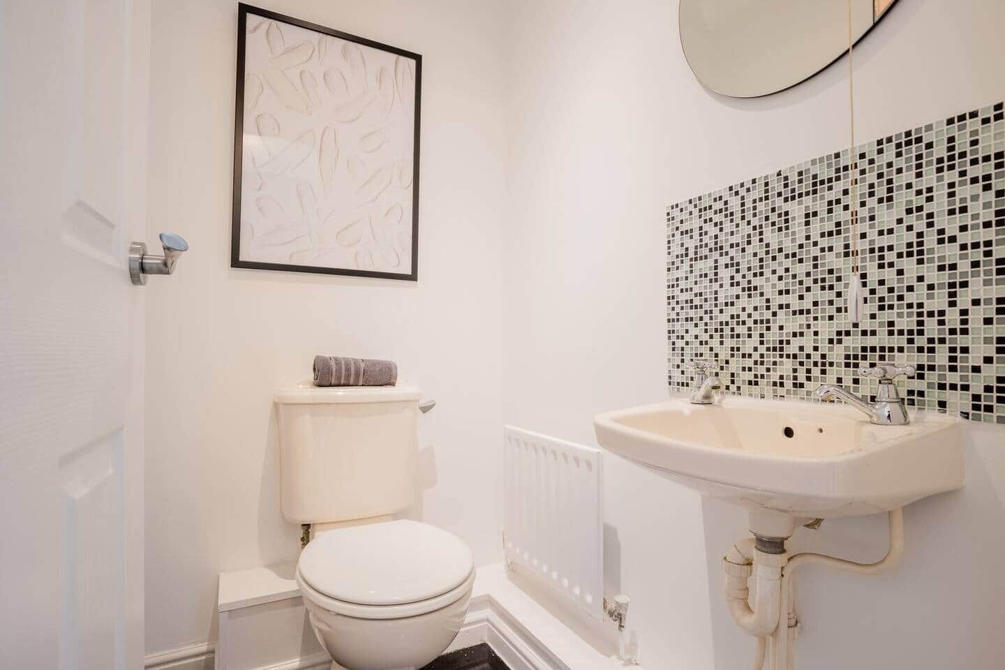 A bathroom with a toilet, a sink, and a mirror.