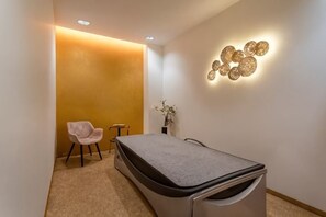A room with a bed, a chair, a small table, and a wall-mounted light fixture. - Hotel Behounek (Karlovy Vary District)