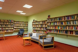 A library with bookshelves, seating, and a carpeted floor. - Hotel Behounek (Karlovy Vary District)