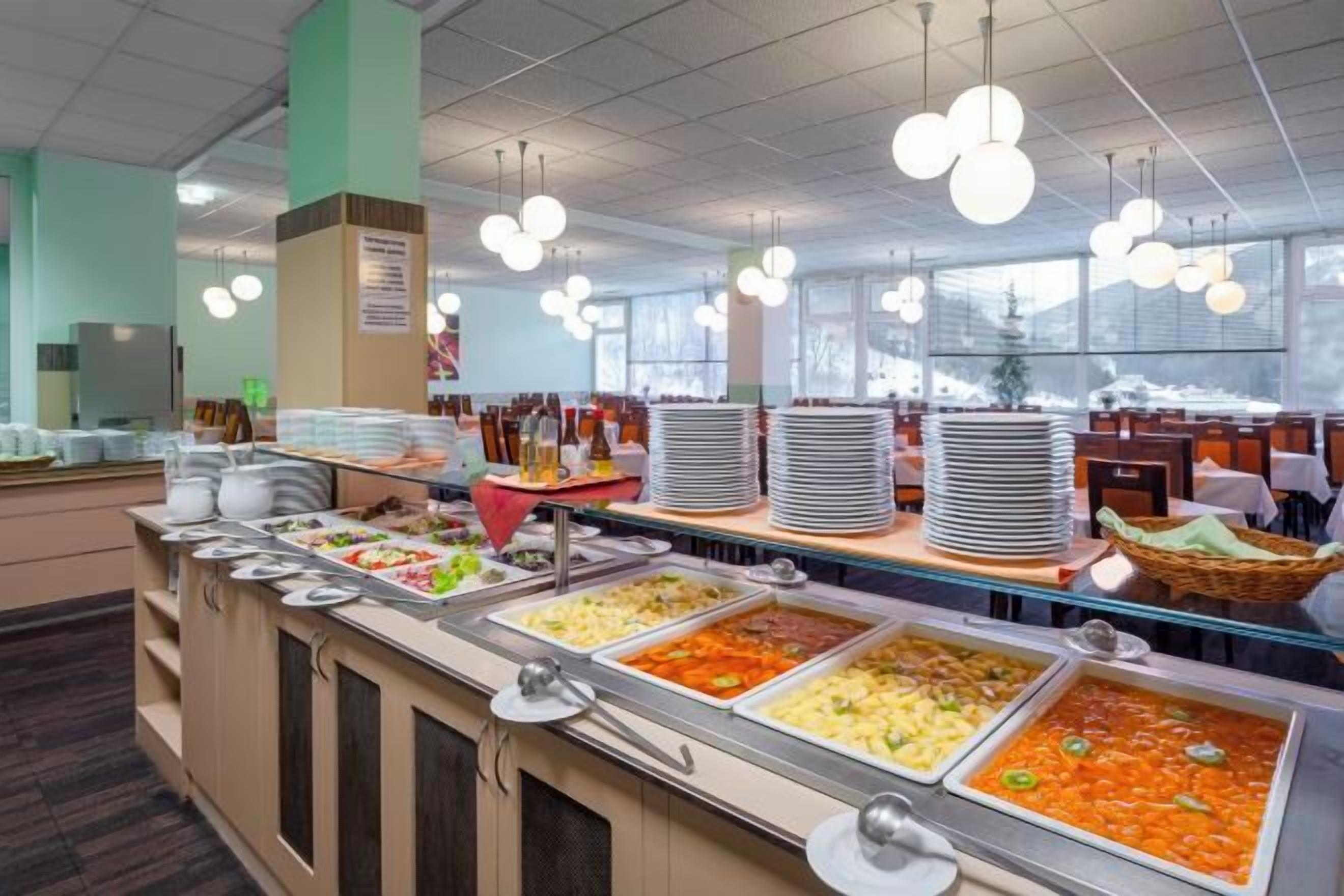 A buffet area with multiple food stations, a seating area, and a large window providing natural light.