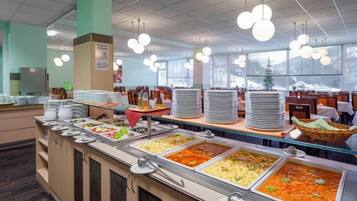 A buffet area with multiple food stations, a seating area, and a large window providing natural light.
