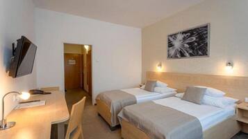 A hotel room with two beds, a desk with a chair, a TV, and a painting on the wall.
