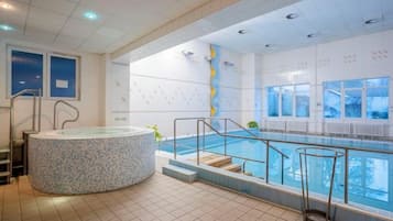 Una piscina con un jacuzzi, escaleras que conducen a la piscina y vistas al exterior a través de amplias ventanas.