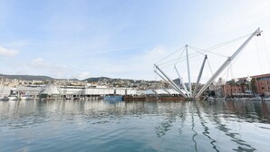 Ein Hafen mit Booten, eine große weiße Struktur und eine Stadtlandschaft im Hintergrund.