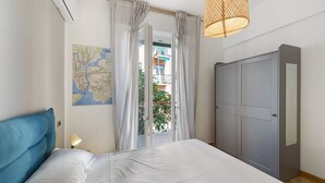 Ein Schlafzimmer mit einem Bett, Vorhängen, einer Karte an der Wand und einem Kleiderschrank.