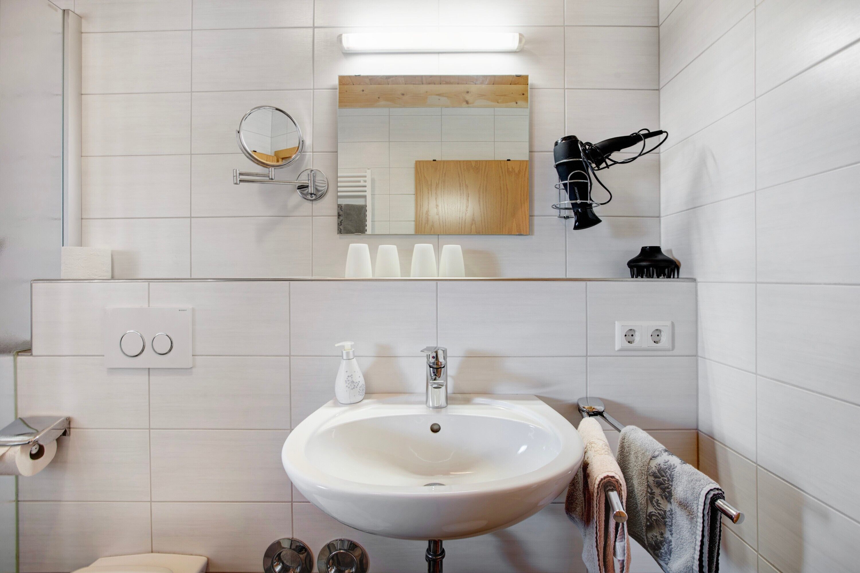 Een badkamer met een wastafel, spiegel, haardroger en handdoekrek.