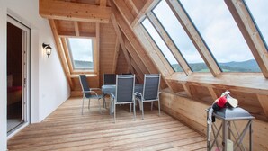 En træterrasse med et bord og stole, en lygte og udsigt gennem ovenlys.