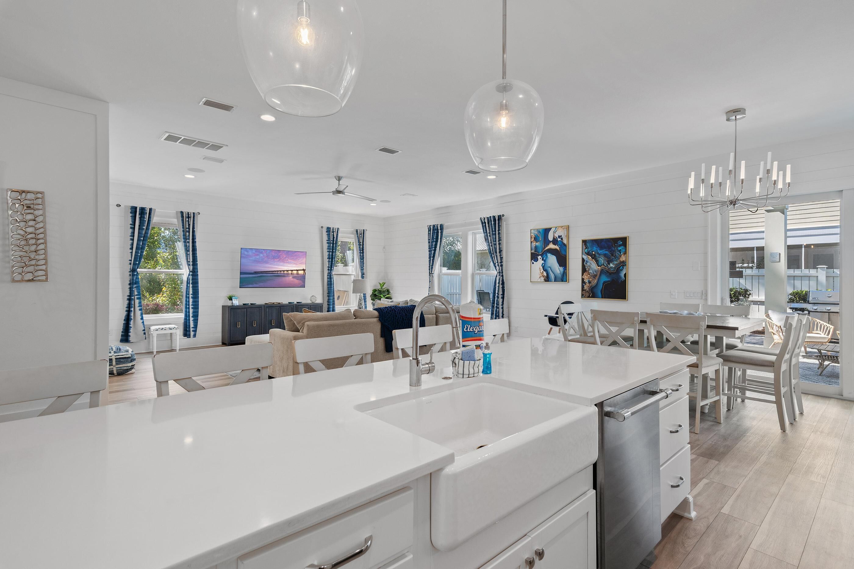 A modern kitchen with white cabinetry, a central island with a sink, and pendant lighting.