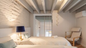 Een hotelkamer met twee bedden, een stoel, een lamp en uitzicht op een gebouw.
