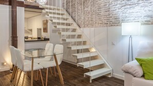 Een modern interieur met een trap, een eetgedeelte met een glazen tafel en een witte bank.