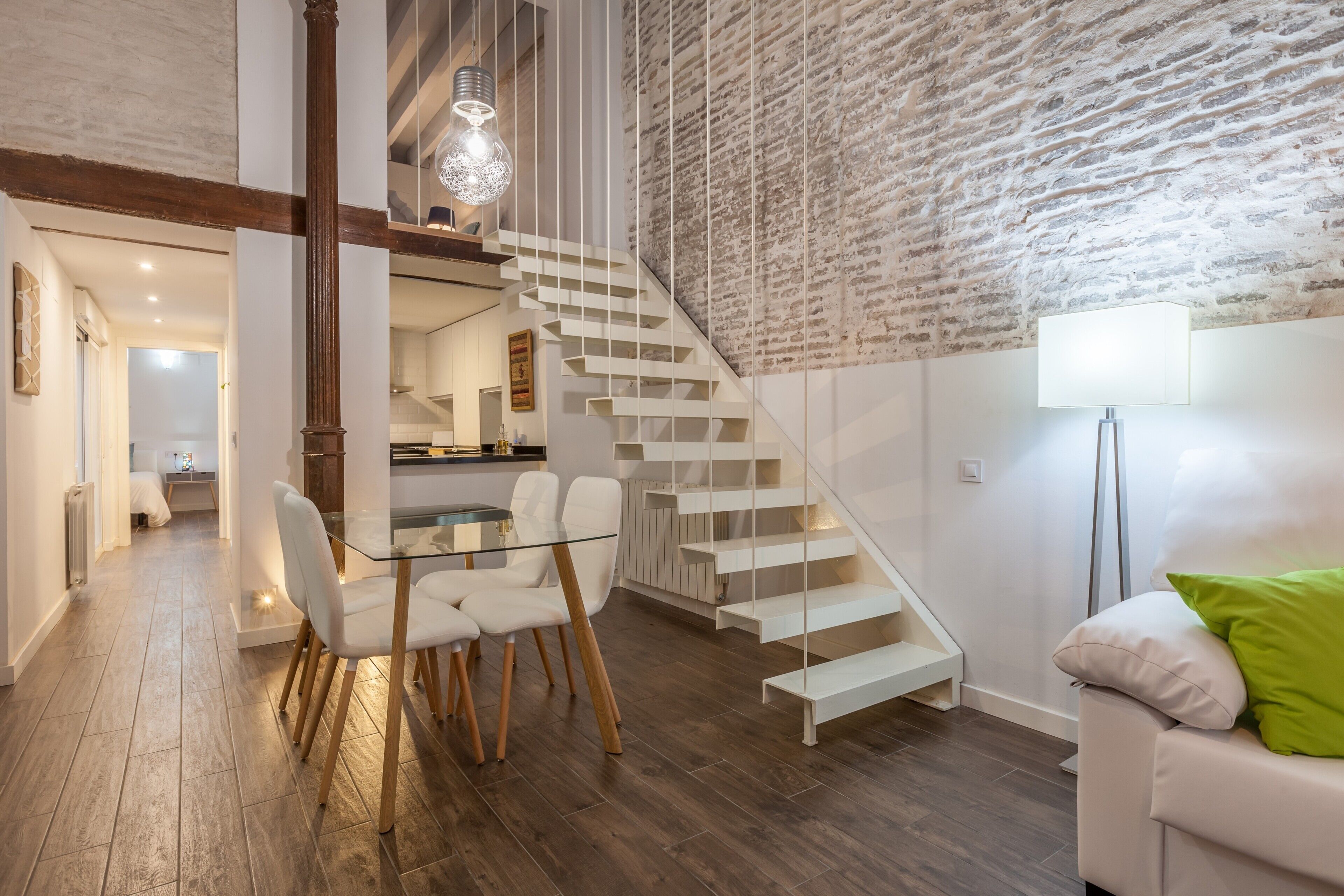 Un interior moderno con una escalera, zona de comedor y sofá.
