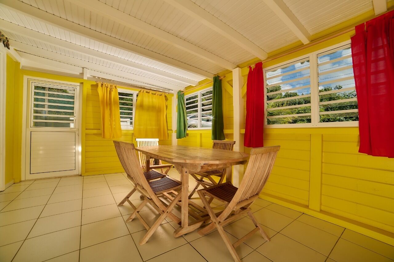 Un coin repas avec une table et des chaises en bois, des murs jaunes et des fenêtres avec des rideaux.