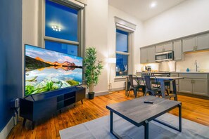 Een moderne woonkamer met een flatscreen televisie, een eethoek en een keuken.