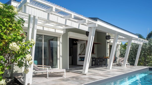 Ein modernes Haus mit Pool, inklusive einer Terrasse mit Sitzgelegenheit und einem Eingang mit Glasdoor.