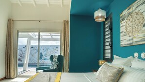 Ein Schlafzimmer mit einem Bett, einem Sessel, einem Fenster und einem Bild an der Wand.