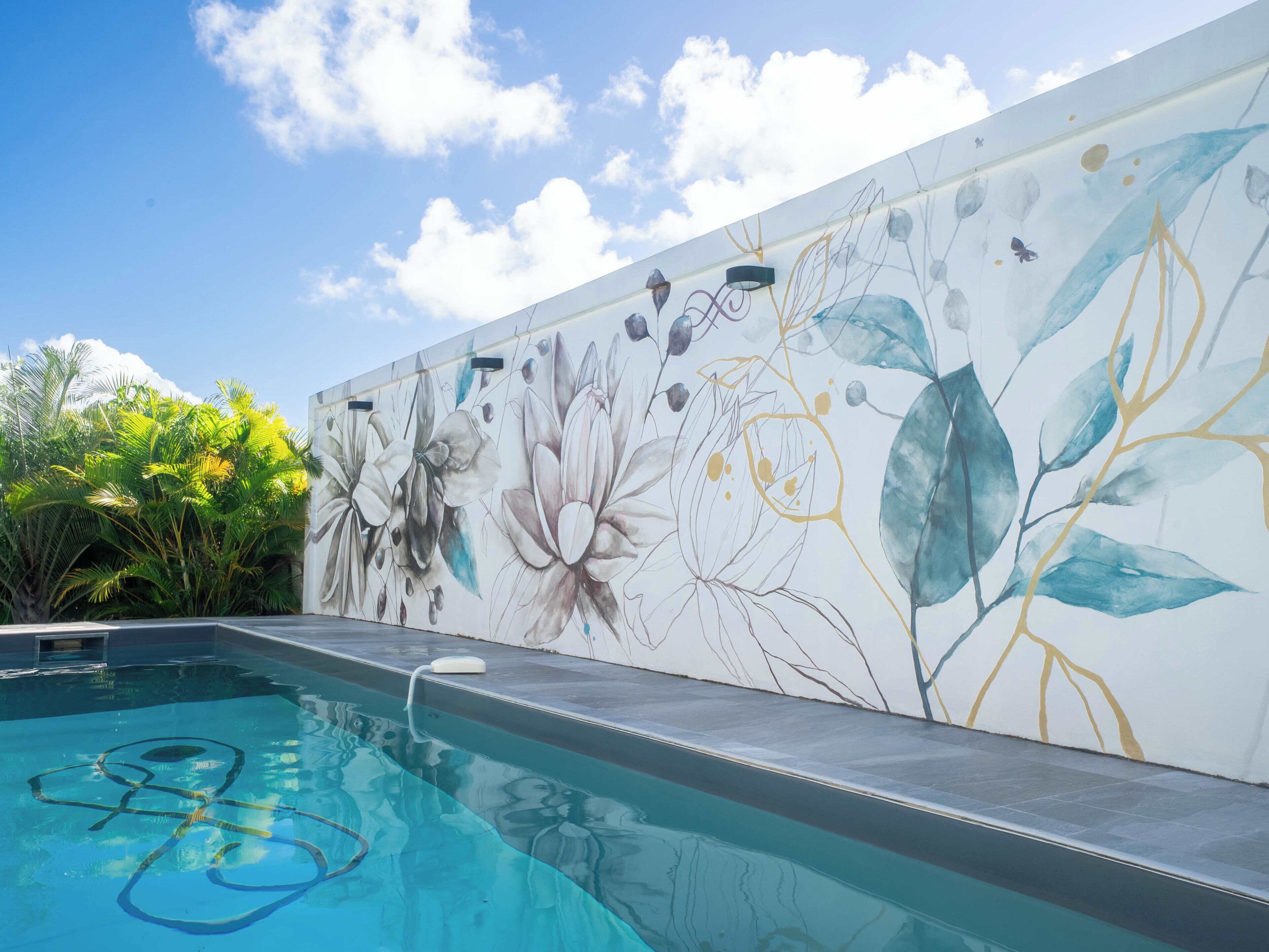 A swimming pool with a mural of flowers and leaves on the adjacent wall.