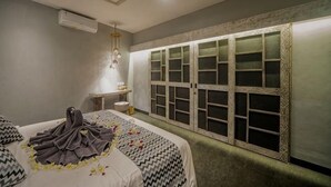 Un dormitorio con cama, tocador y ventana con contraventanas decorativas.