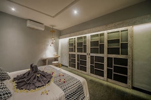 Une chambre d’hôtel avec un lit, une coiffeuse et une fenêtre agrémentée de volets décoratifs.