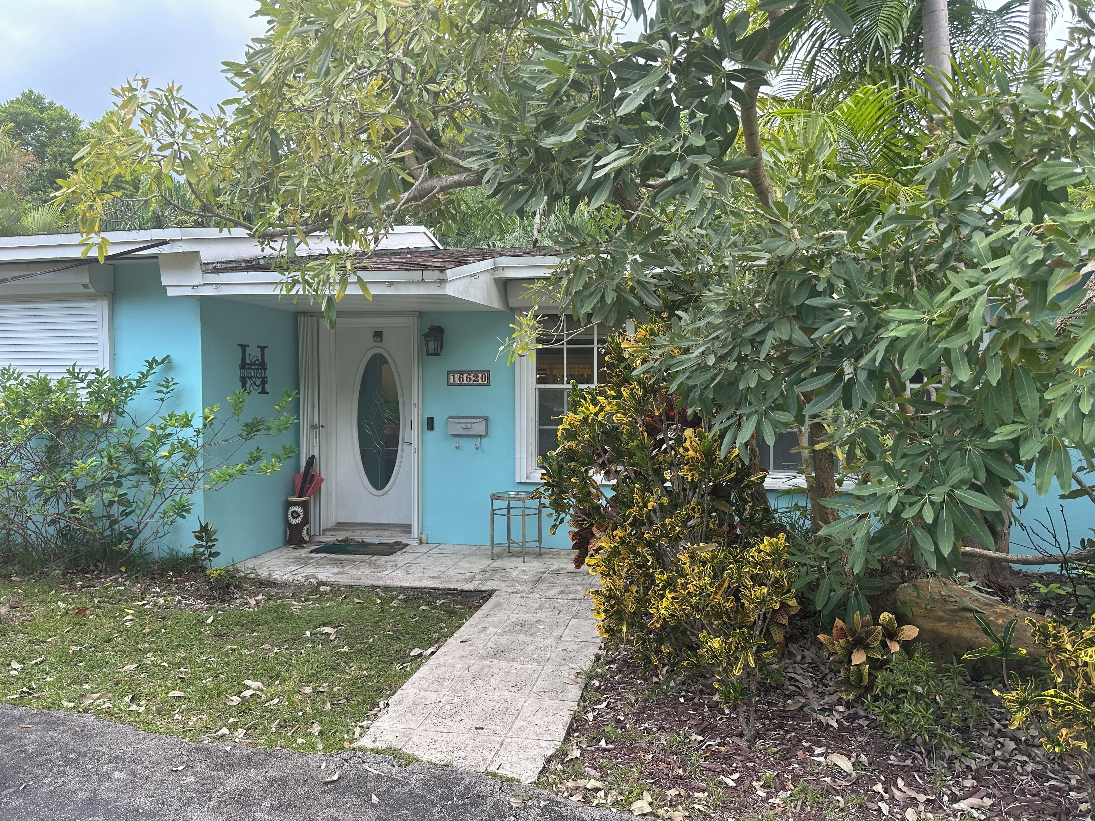 A house with a blue exterior, a white door, and a mailbox with the number 16620.