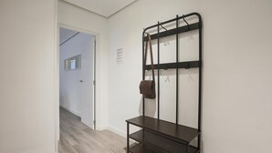 Ein Flur mit einem an der Wand befestigten Gepäckträger und einer kleinen Bank.