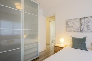 Una camera d'albergo con un letto, un comodino con una lampada, una porta scorrevole e un quadro appeso al muro.